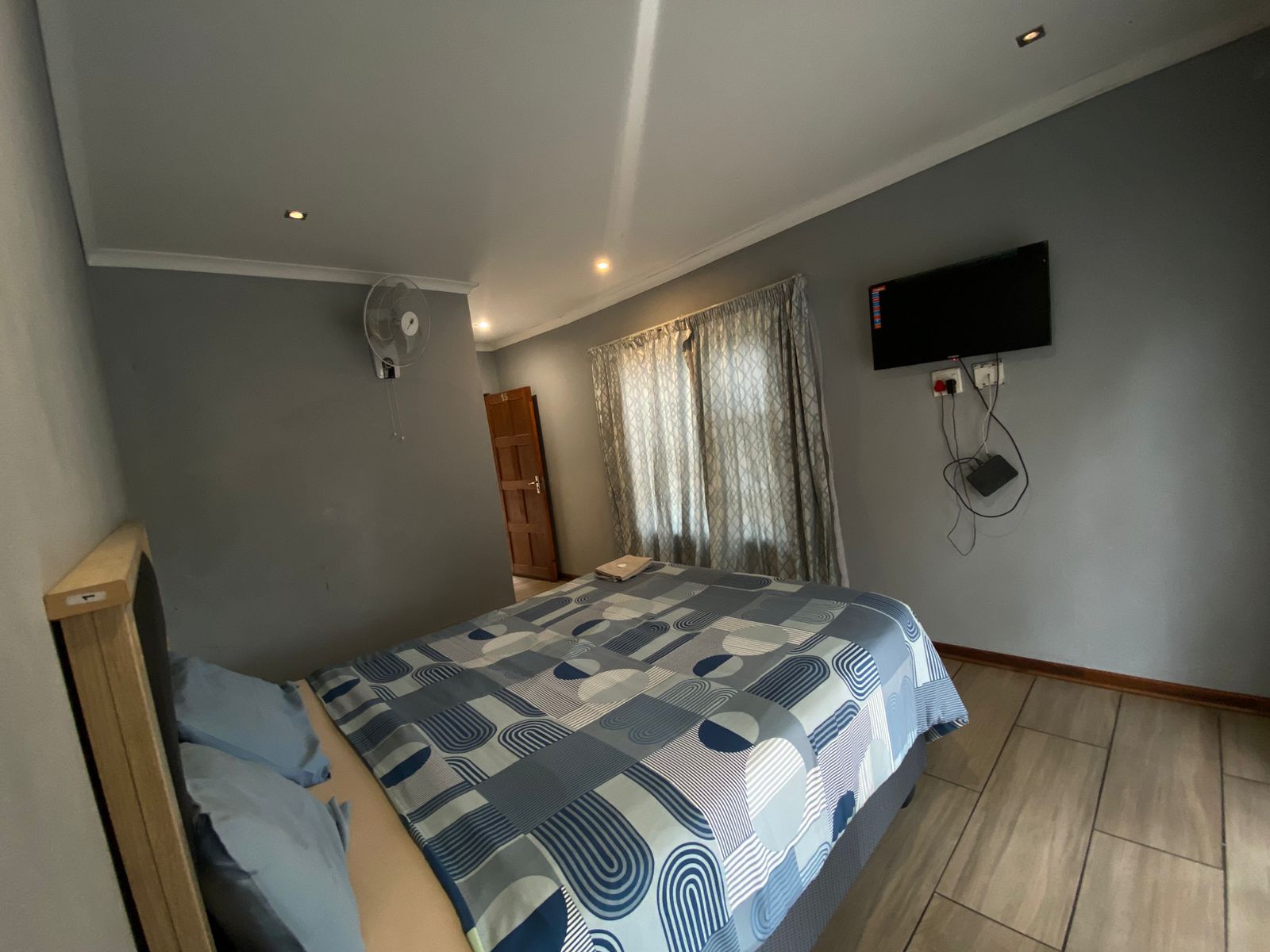 Modern room with light wood headboard, wall fan and blue circular bedding