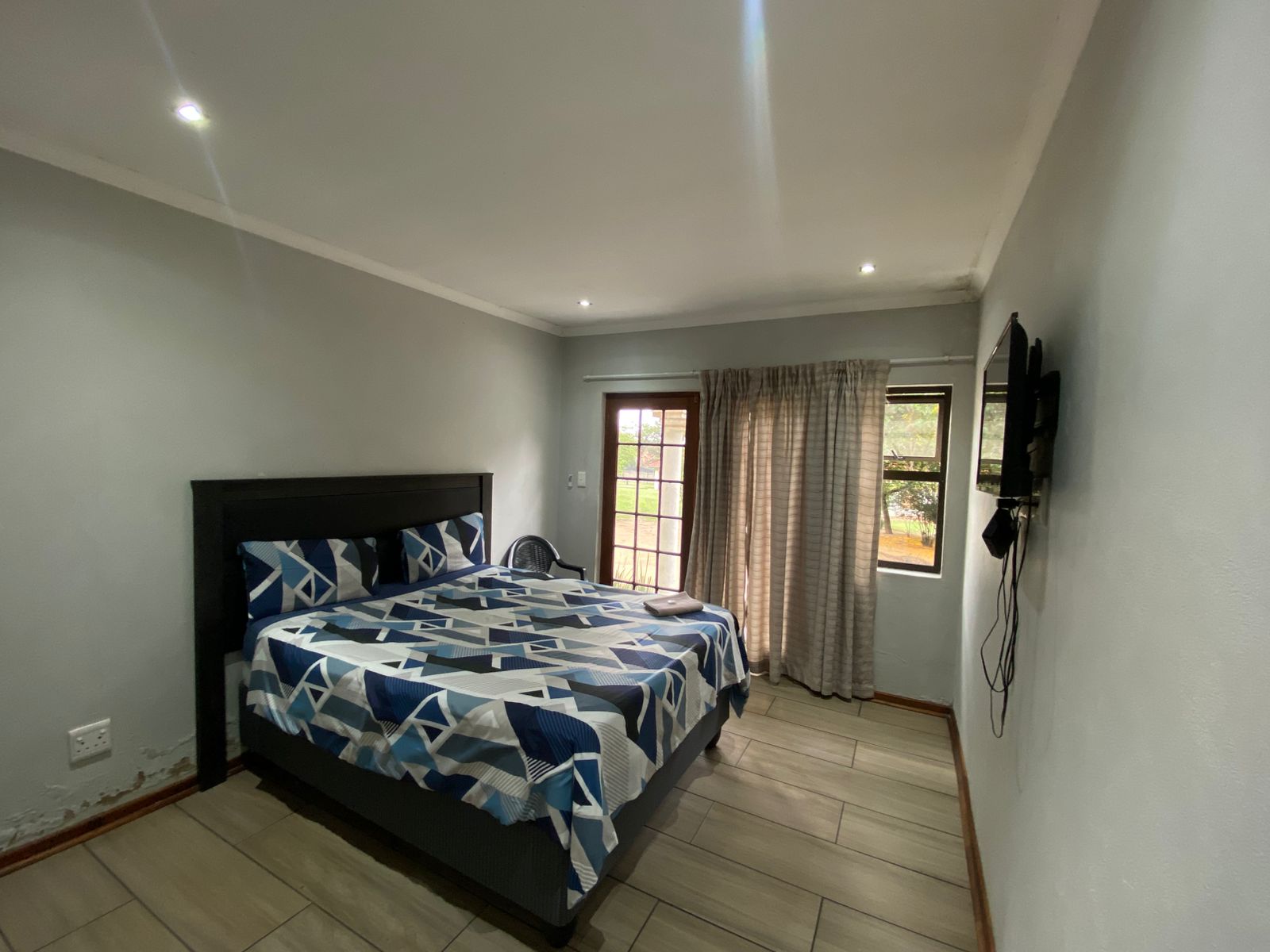Bright room with black headboard, multiple windows and French door access