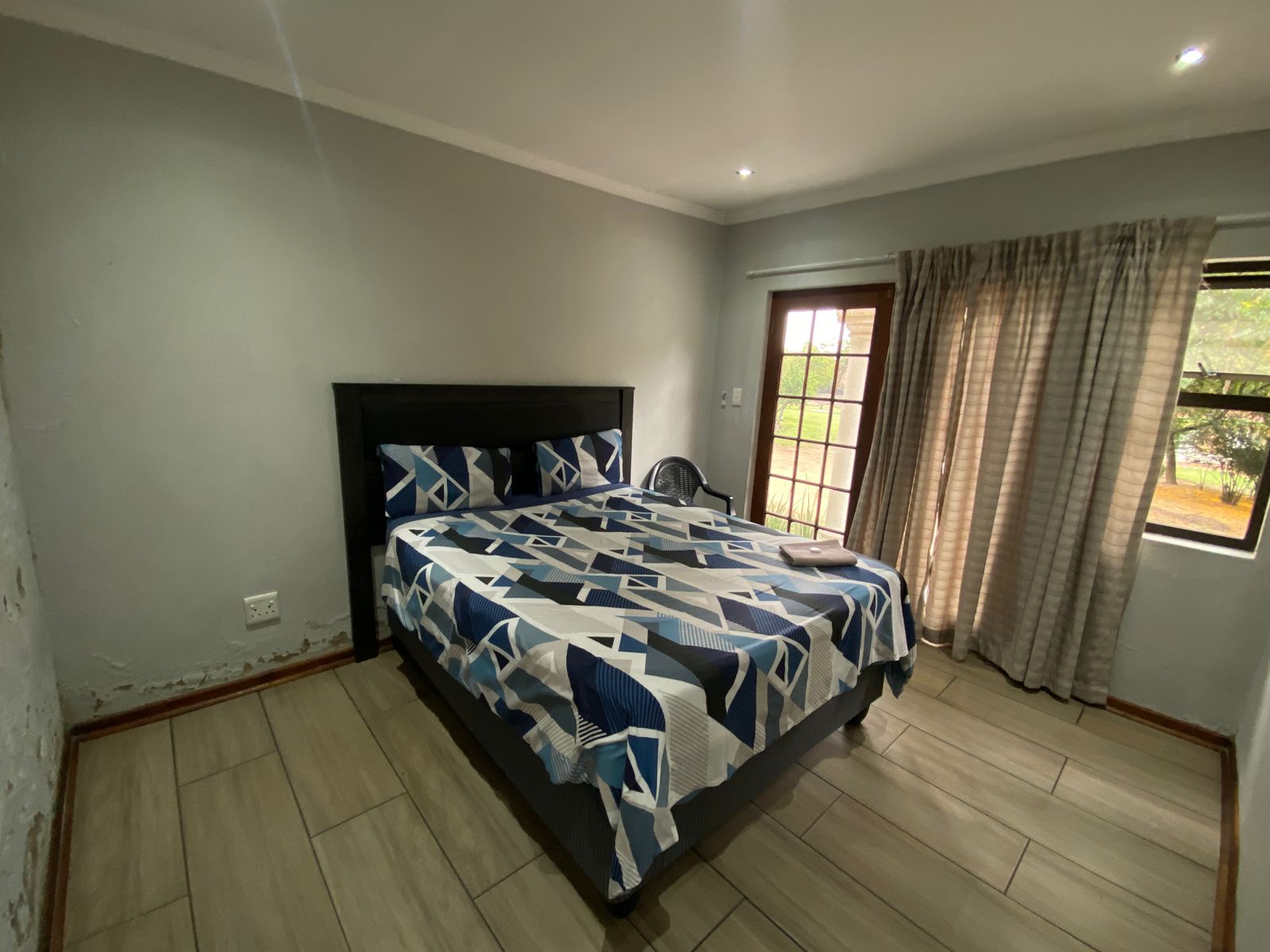 Spacious room with black headboard, French doors and garden view