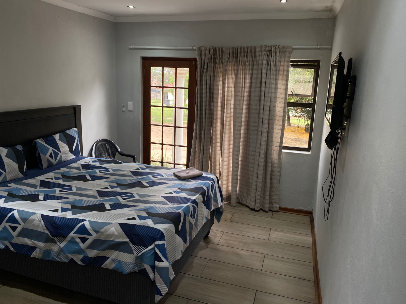 Elegant room with black headboard, queen bed and blue geometric triangle bedding