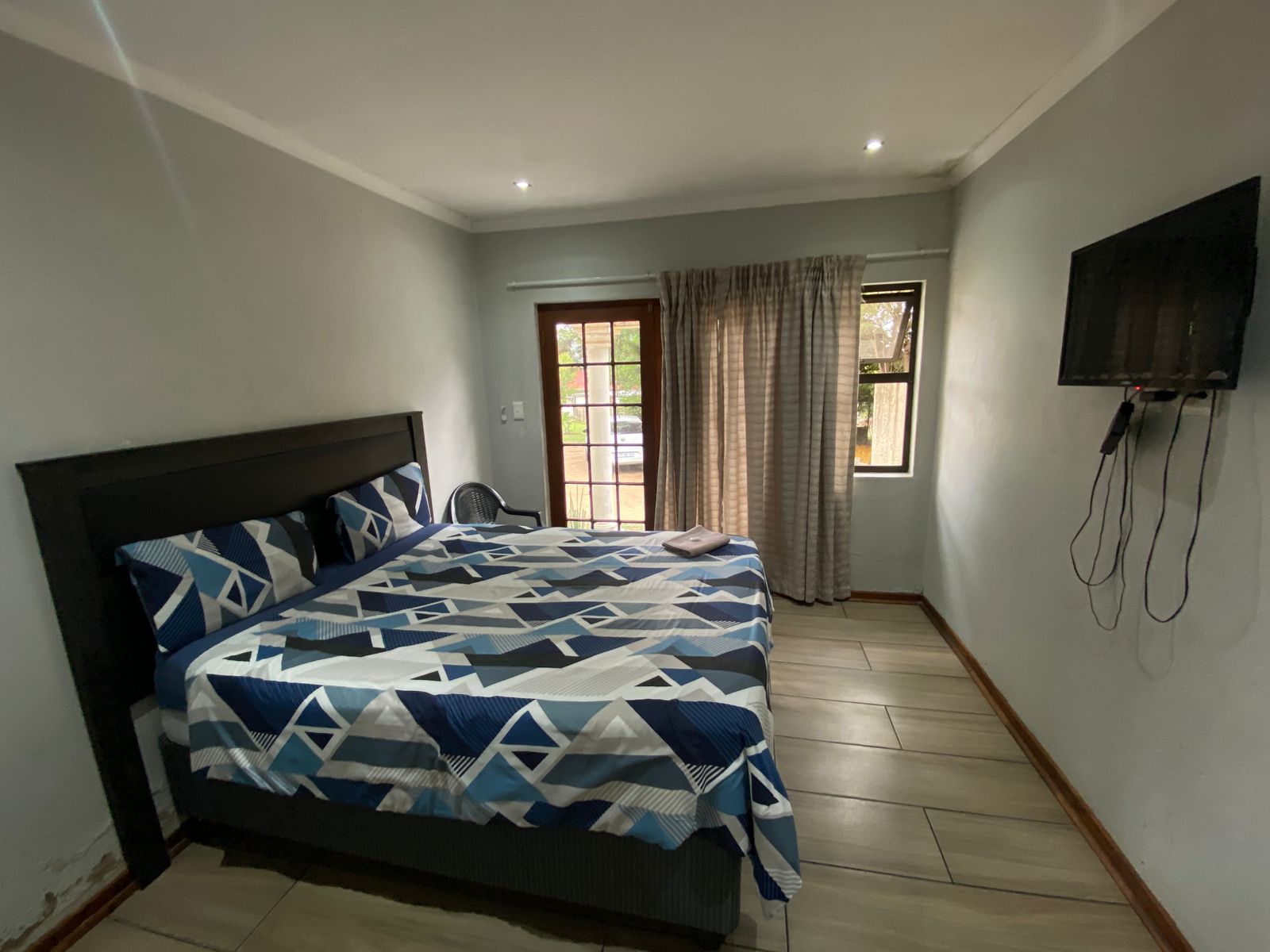 Queen bed room with black headboard, elegant blue and white geometric bedding